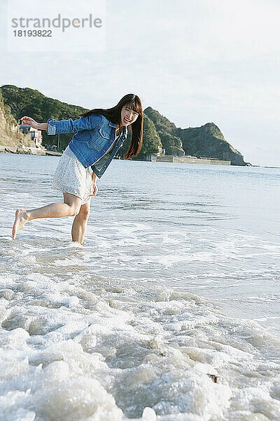 Junge Japanerin hat Spaß am Strand