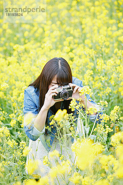 Junge Japanerin fotografiert in einem Blütenfeld