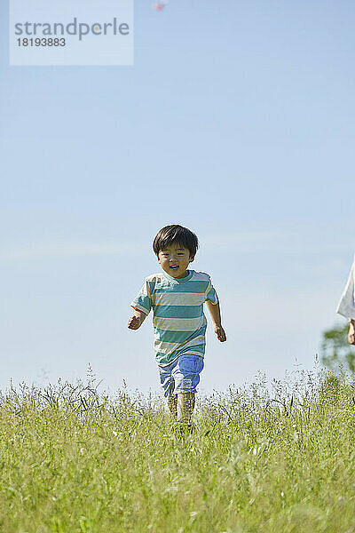 Japanischer Junge läuft auf dem Feld