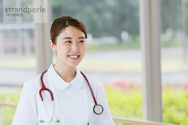 Lächelnde junge japanische Krankenschwester im Flur