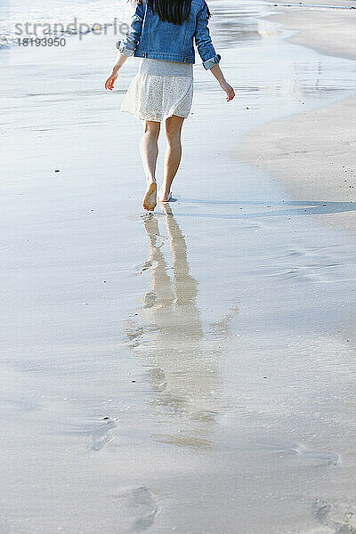 Die Füße einer jungen Frau  die am Strand spaziert