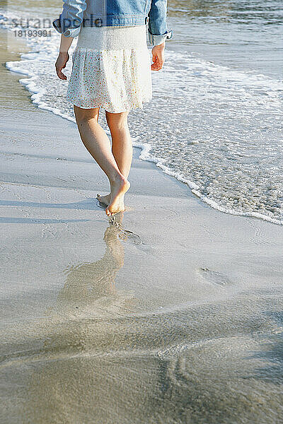Die Füße einer jungen Frau  die am Strand spaziert