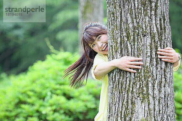 Japanerin umarmt einen Baum