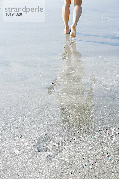 Die Füße einer jungen Frau  die am Strand spaziert