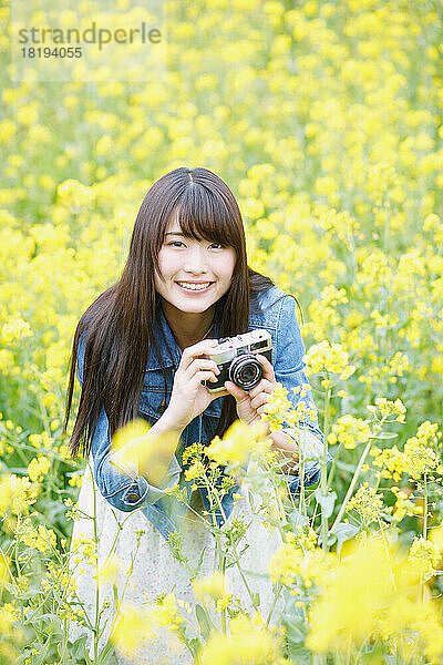 Junge Japanerin fotografiert in einem Blütenfeld