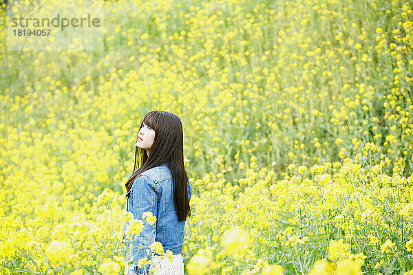 Eine junge Japanerin steht in einem Blütenfeld