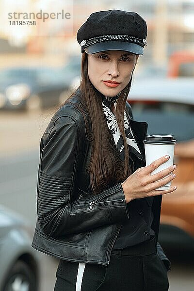 Attraktives Mädchen geht mit einer Tasse Kaffee die Straße entlang
