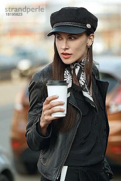 Attraktives Mädchen geht mit einer Tasse Kaffee die Straße entlang