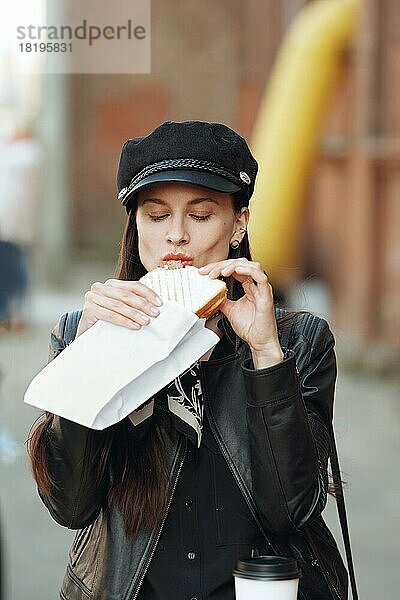 Attraktives Mädchen isst Sandwich auf der Straße