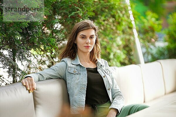 Lifestyle-Porträt eines Mädchens  das im Sommer auf der Terrasse eines Cafés sitzt