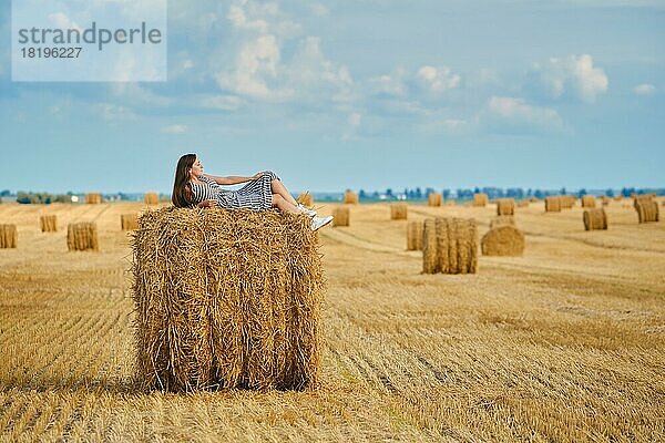 Ruhige junge Frau  die auf einem Strohhaufen auf dem Feld liegt