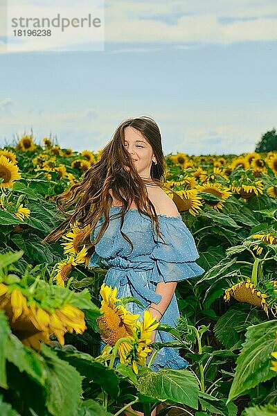Unbekümmerte junge Frau tanzt in einem Sonnenblumenfeld