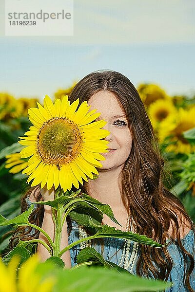 Schöne junge Frau  die die Hälfte ihres Gesichts mit einer Sonnenblume verdeckt