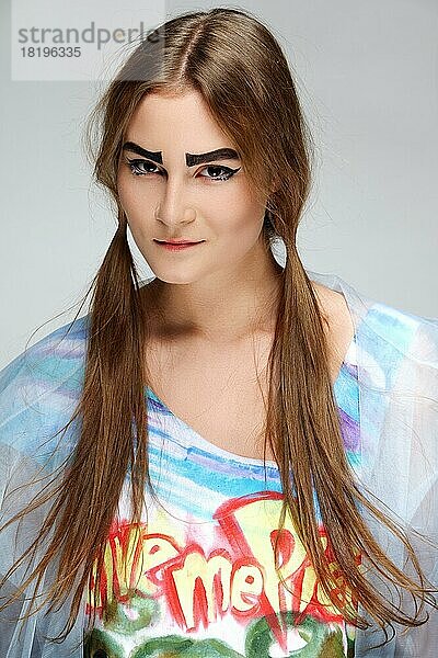 Mädchen mit buschigen Augenbrauen und Zöpfen im Hippie-Kleid. Dunkle Augen und natürliches Make-up