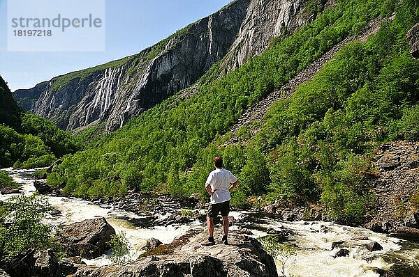 Mann steht in einer Felsenschlucht mit Wasserfall in Norwegen