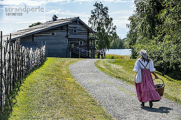 Traditionell gekleidete Frau auf dem Weg zu einem Holzhaus  Unesco-Stätte Insel Kizhi  Karelien  Russland  Europa