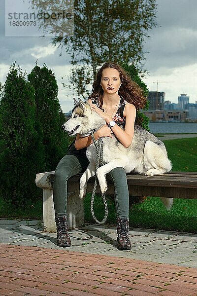 Mädchen mit Husky-Hund im Stadtpark sitzend. Hund auf einer Bank