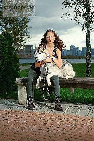 Mädchen mit Husky-Hund im Stadtpark sitzend. Hund auf einer Bank