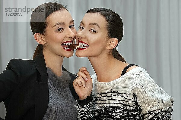 Zwei junge Mädchen essen ein Bonbon von Mund zu Mund