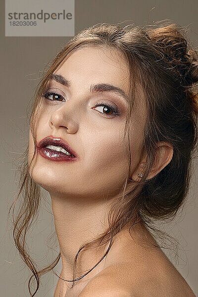 Porträt eines schönen Mädchens mit sauberer Haut und schmierendem Lippenstift. Gefiederte Lippen und eine Haarsträhne