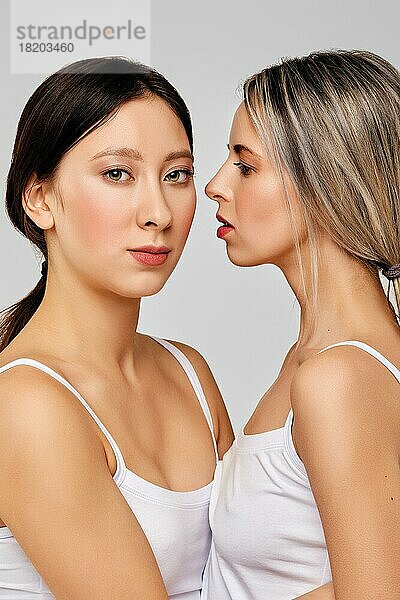 Schöne kaukasische junge Frauen schaut auf ihre asiatische Freundin  die nahe beieinander steht