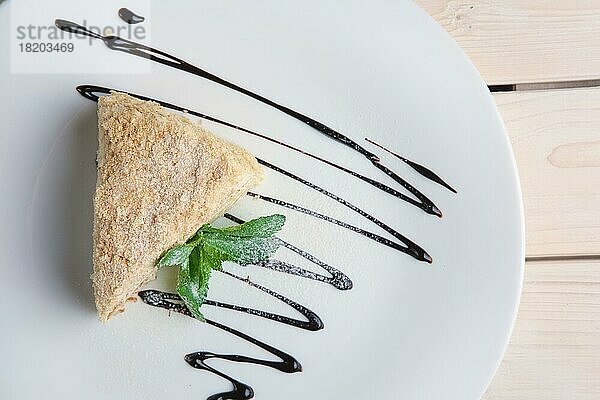 Draufsicht auf Napoleonkuchen auf Teller mit Schokoladensauce. Blätterteigkuchen mit Pudding