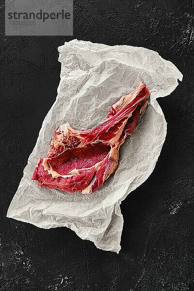 Draufsicht auf Rinder-Ribeye-Steak mit Knochen auf Einwickelpapier
