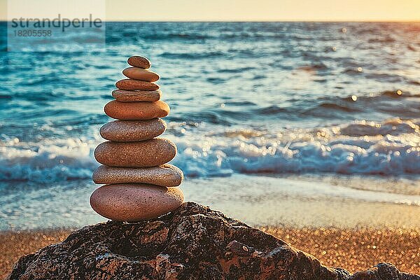 Konzept der Balance und Harmonie. Cairn Stapel von Steinen Kieselsteine Steinhaufen am Strand Küste des Meeres in der Natur auf Sonnenuntergang. Meditative Kunst des Steinstapelns