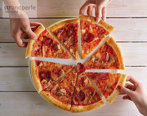 Nahaufnahme von Menschen  die sich Pizzastücke in die Hand nehmen. Essen teilen. Gruppe von Freunden essen Pizza zusammen