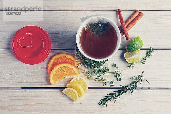 Draufsicht auf einen Tisch mit Kräutertee mit Orange  Limette und Zitrone in einer Tasse zum Mitnehmen