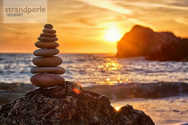 Konzept der Balance und Harmonie. Cairn Stapel von Steinen Kieselsteine Steinhaufen am Strand Küste des Meeres in der Natur auf Sonnenuntergang. Meditative Kunst des Steinstapelns