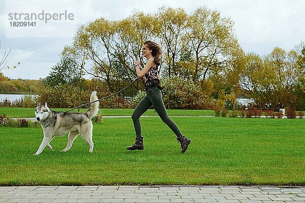 Mädchen spielt mit Husky-Hund im Stadtpark. Joggen mit Hund