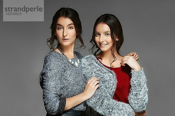 Zwei junge Schwestern in warmen Wollpullovern umarmen sich gegenseitig