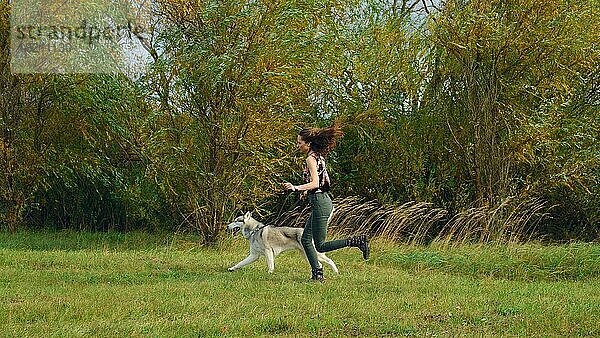 Mädchen spielt mit Husky-Hund im Stadtpark. Joggen mit Hund