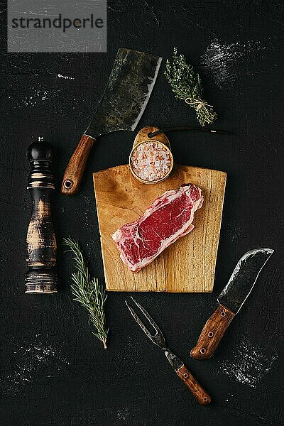 Draufsicht auf rohes Strip Steak ohne Knochen auf dunklem Hintergrund