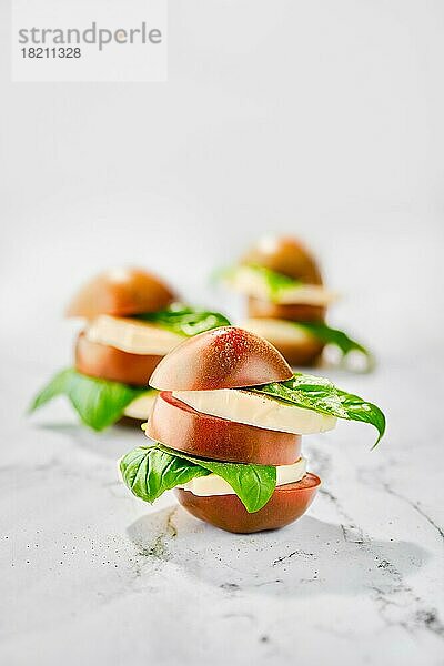 Braune Schokoladentomate  Mozzarella und Basilikum in Scheiben geschnitten und auf Marmoruntergrund gestapelt (Foto mit geringer Tiefenschärfe)