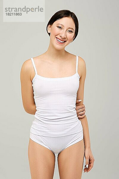 Nettes und glückliches asiatisches Mädchen in weißem T-Shirt und natürlichem Make-up