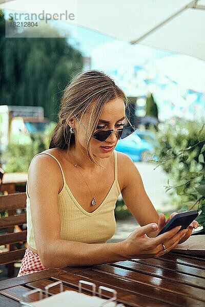 Überrumpelte Frau liest Nachrichten auf ihrem Smartphone im Freien