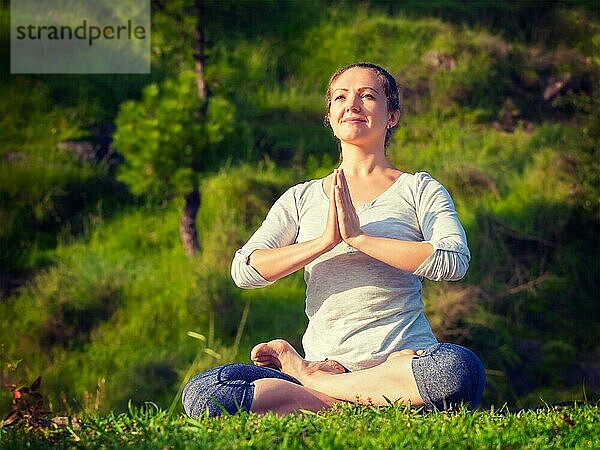 Meditation und Entspannung Yoga im Freien  junge Frau meditiert und entspannt in Padmasana Lotus Pose) mit Namaste Mudra auf grünem Gras im Wald. Vintage Retro-Effekt gefiltert Hipster-Stil Bild