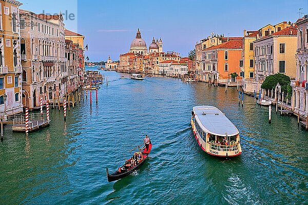 VENEDIG  ITALIEN  19. JULI 2019: Blick auf den Canal Grande di Venezia mit Gondel und Vaporetto und die Kirche Santa Maria della Salute bei Sonnenuntergang von der Brücke Ponte dell'Accademia. Venedig  Italien  Europa