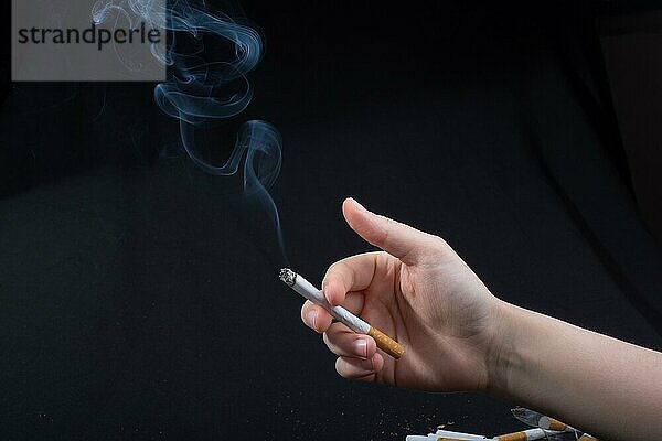 Hand hält rauchende Zigarette mit Rauch um
