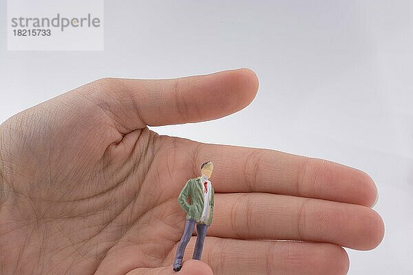 Hand hält eine menschliche Figur auf weißem Hintergrund
