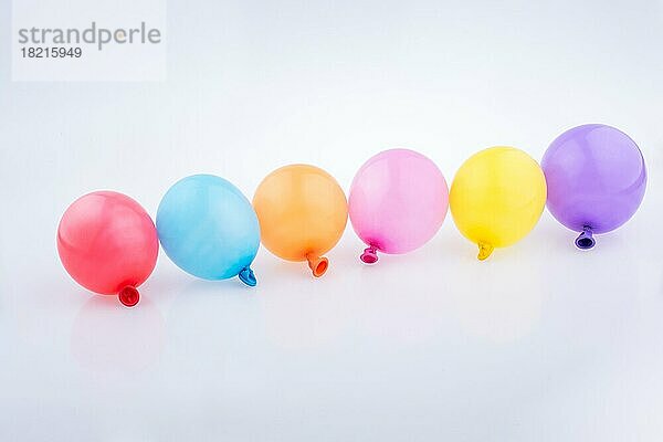 Bunte kleine Luftballons in einer Reihe auf einem weißen Hintergrund