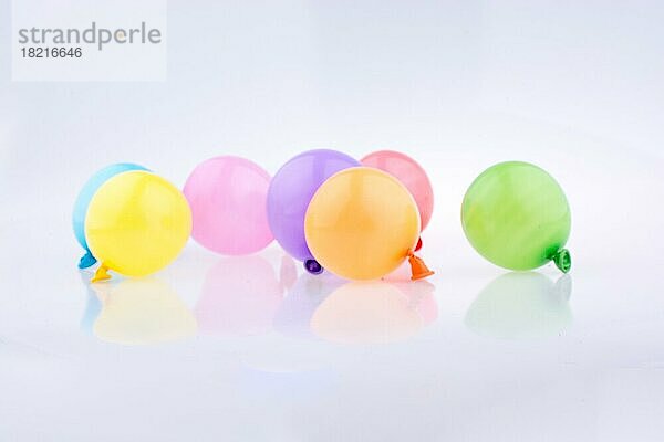 Kleine Luftballons in verschiedenen Farben auf weißem Hintergrund