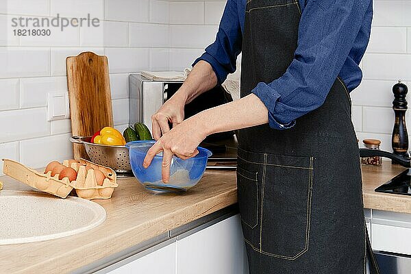 Nahaufnahme der Hände eines Mannes  der ein Ei mit einem Schneebesen aufschlägt  um ein Omelett zu machen