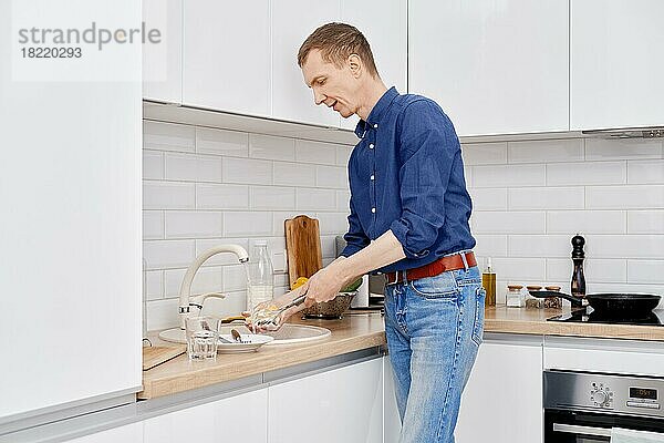 Ein Mann mittleren Alters wäscht nach dem Kochen zu Hause das Geschirr ab
