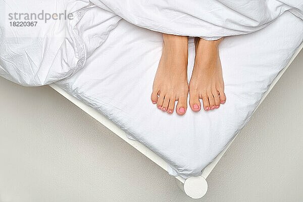 Draufsicht auf die weiblichen Fußsohlen  die unter der Decke hervortreten