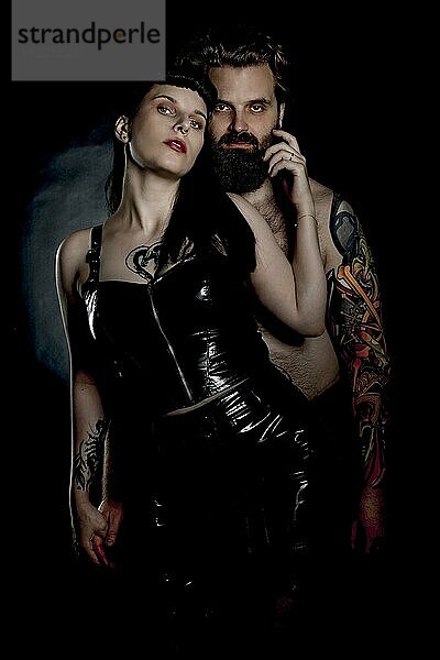 BDSM Paar  Mann mit Tattos und Frau in Lack und Latex Outfit
