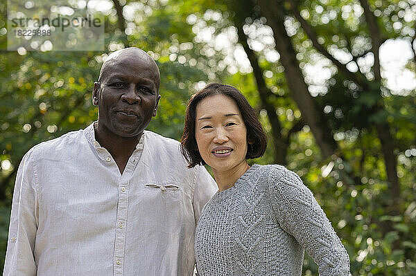 Portrait of middle-age African American man and Asian American woman outdoors in public park