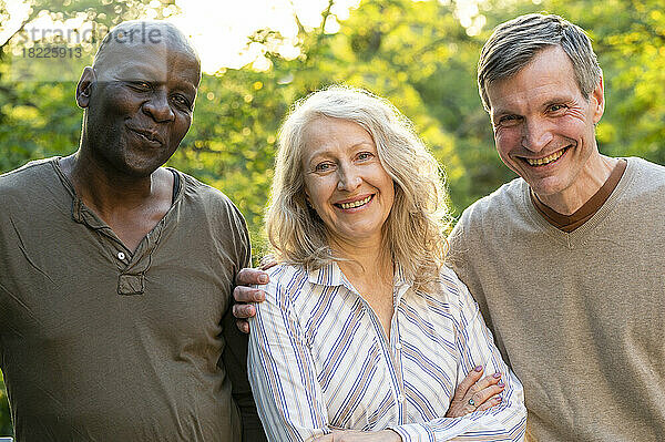 Senior lady posing with her two male friends while hanging out in her backyard at sunset